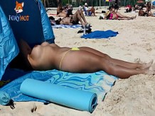 Tomando el sol en topless en la playa para ser observada por otros hombres