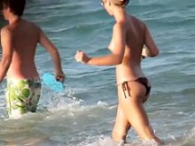 Chica en topless jugando en la playa y siendo voyeurizada