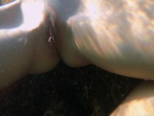 Chica delgada nada desnuda en el mar y se masturba el coño