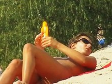 Una mujer lujuriosa tomando el sol en este video voyeur de playa nudista