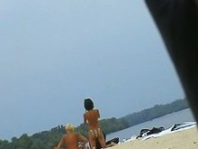 Bellezas elegantes en topless en la playa nudista siendo filmadas por un voyeur