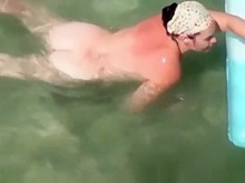 Mujer nudista nadando en la playa