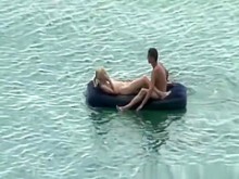 Grupo de nudistas en colchón de aire en el agua.