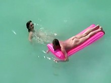 Nudista de tetas pequeñas nadando en el agua