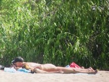Cazador nudista en la playa mirando cuerpos desnudos detrás de los arbustos