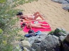 Dos chicas desnudas tomando el sol en la playa.