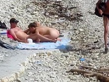 Chica sensual salta sobre la polla gorda de su novio en la playa nudista