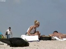 Rubia sexy relajándose en la playa nudista mientras espío con mi cámara