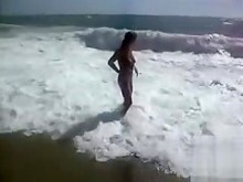 La parte inferior de un bikini de morena tetona cae cuando enormes olas la golpean