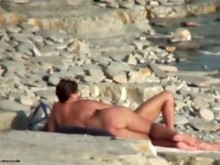 Puma caliente está acostado en la arena en un video de playa desnuda