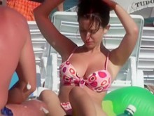 Atractiva doncella morena se quita la parte superior del bikini en la playa