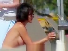 mujer de pelo corto en topless en la playa