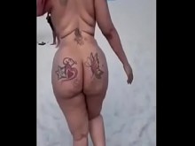 Chica de ébano con gran botín en la playa nudista