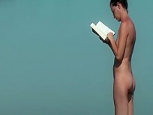 Mujer nudista leyendo un libro en la playa
