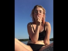Una chica rubia fuma un cigarrillo en la playa. ¿Quieres que empiece a masturbarse ahí mismo?