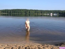Chica sexy se desnuda y nada desnuda en una playa pública