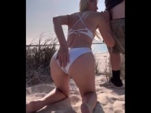 Mamada de puma en la playa al aire libre con bikini blanco