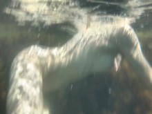 Una niña desnuda nada en el mar y se acaricia bajo el agua