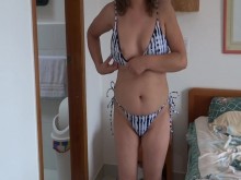 Hermosa madrastra en la playa poniéndose bikini, luciendo buscando a algún chico