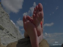 Piernas de la amante descalzas en la playa del mar de verano